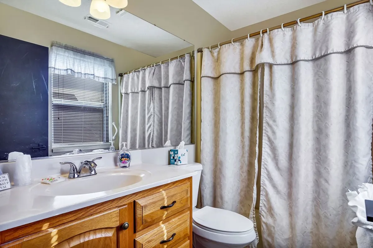 A bright bathroom featuring a vanity sink with a mirrored cabinet, a shower curtain suggesting a combination tub/shower, and refreshing décor. The space feels clean, functional, and inviting, supporting both relaxation and daily routines.