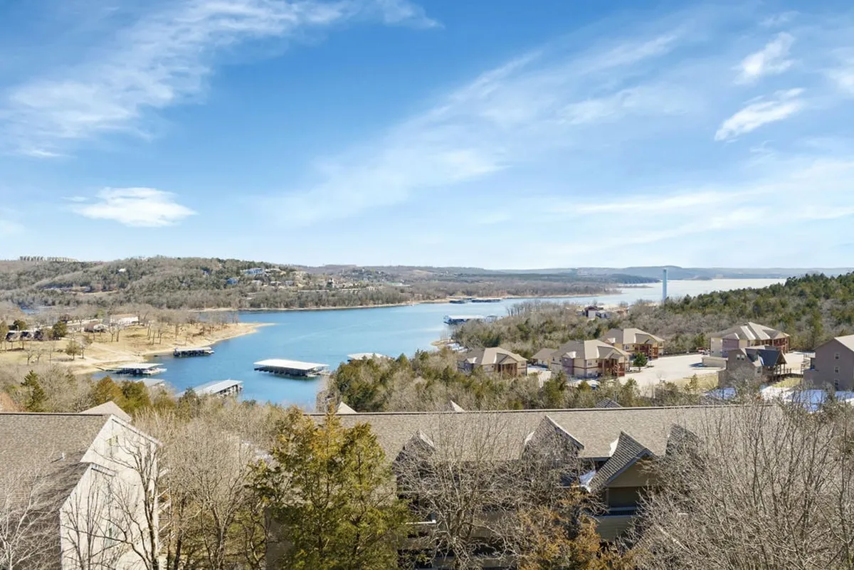 A serene lake view with boats gliding across the water, framed by nearby houses and distant hills. The image captures boating and fishing activities, along with the peaceful charm of lakeside living.