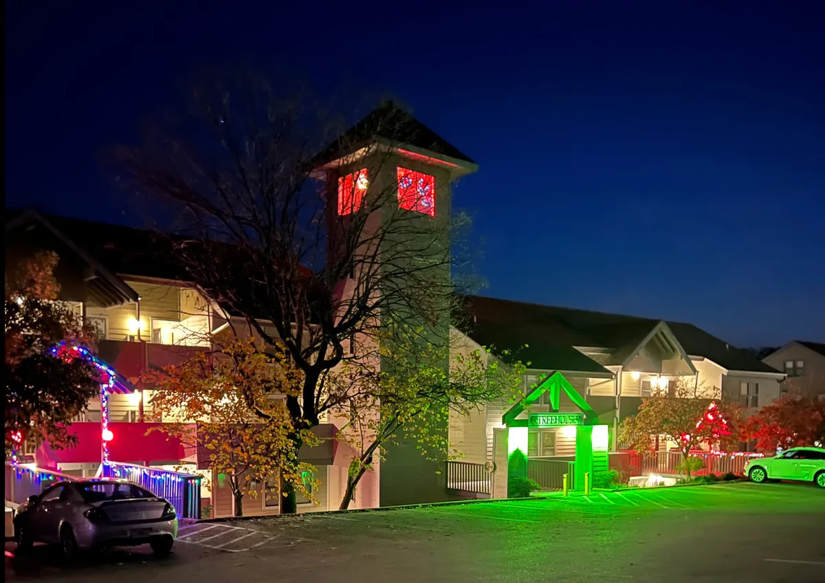 This image features a brightly illuminated clock tower and entrance, festooned with decorative lights, conveying a lively, festive atmosphere. The scene suggests communal enjoyment and hints at seasonal celebrations or evening outings typical of Branson’s entertainment district.